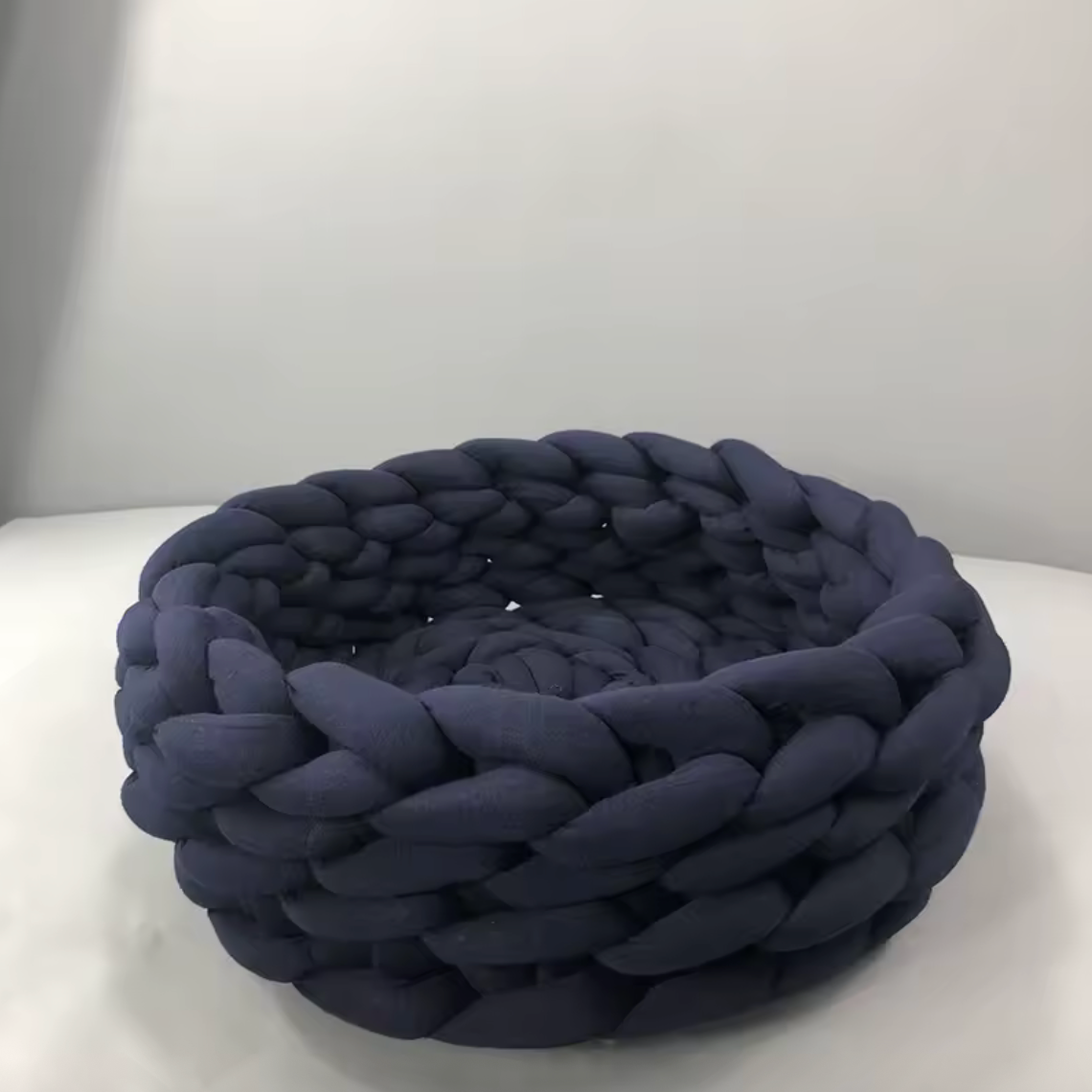 Handgewebtes Katzenbett Grey cat resting in a handmade blue chunky knit cat bed on a light carpet – modern and cozy pet furniture design. Graue Katze liegt entspannt in einem handgewebten, blauen Katzenbett aus dickem Chunky-Strick auf einem hellen Teppich – modernes und gemütliches Design für Haustiere.