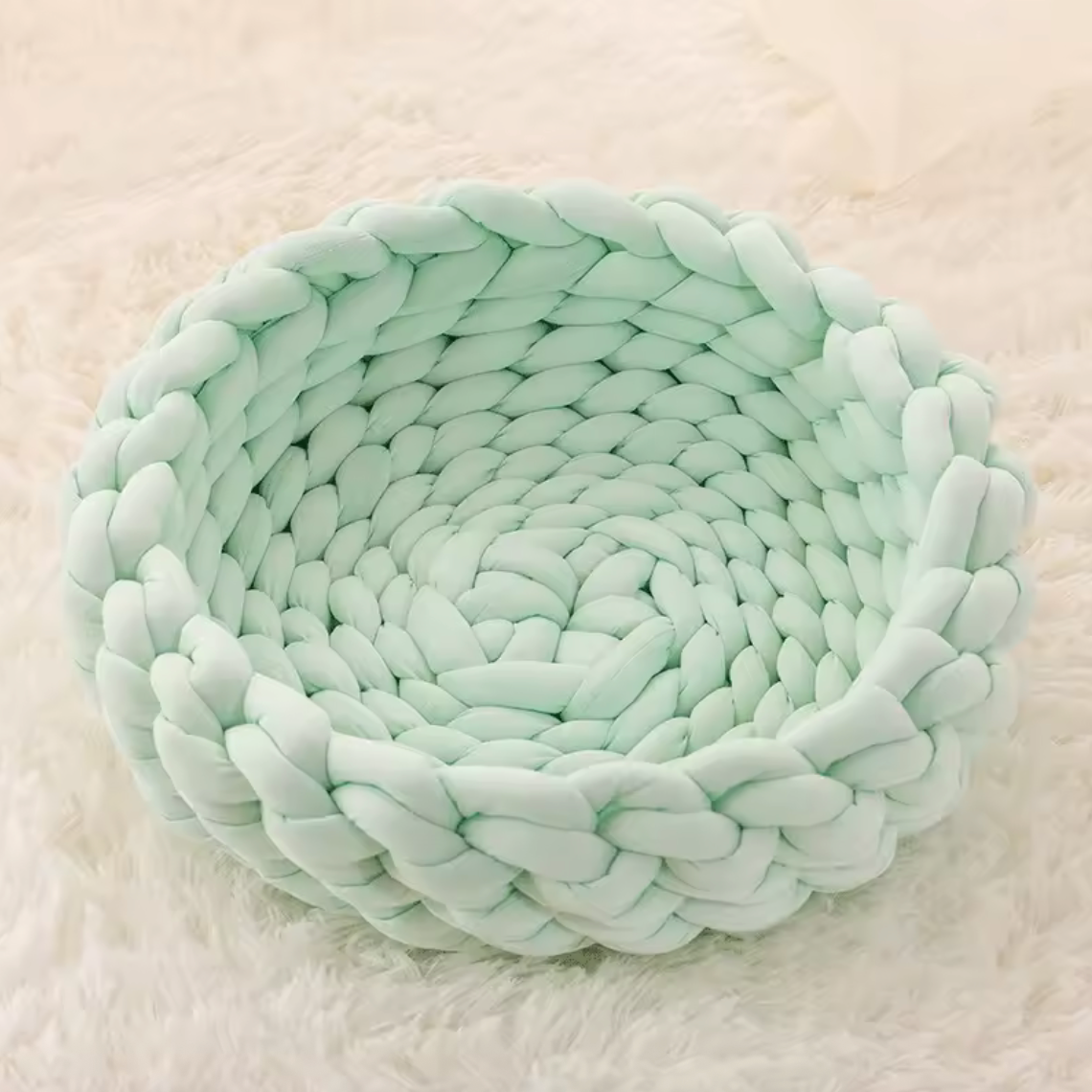 Handgewebtes Katzenbett Grey cat resting in a handmade blue chunky knit cat bed on a light carpet – modern and cozy pet furniture design. Graue Katze liegt entspannt in einem handgewebten, blauen Katzenbett aus dickem Chunky-Strick auf einem hellen Teppich – modernes und gemütliches Design für Haustiere.